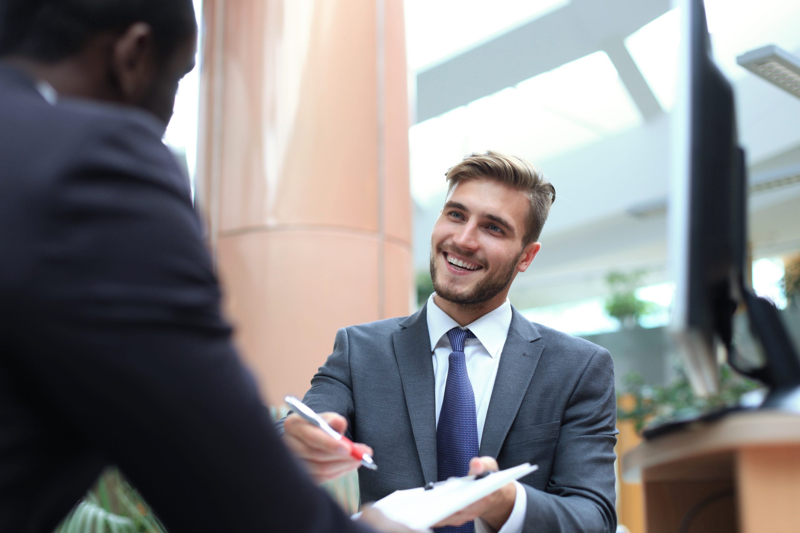 Two multinational young businessmen in suit in the office sign the contract.