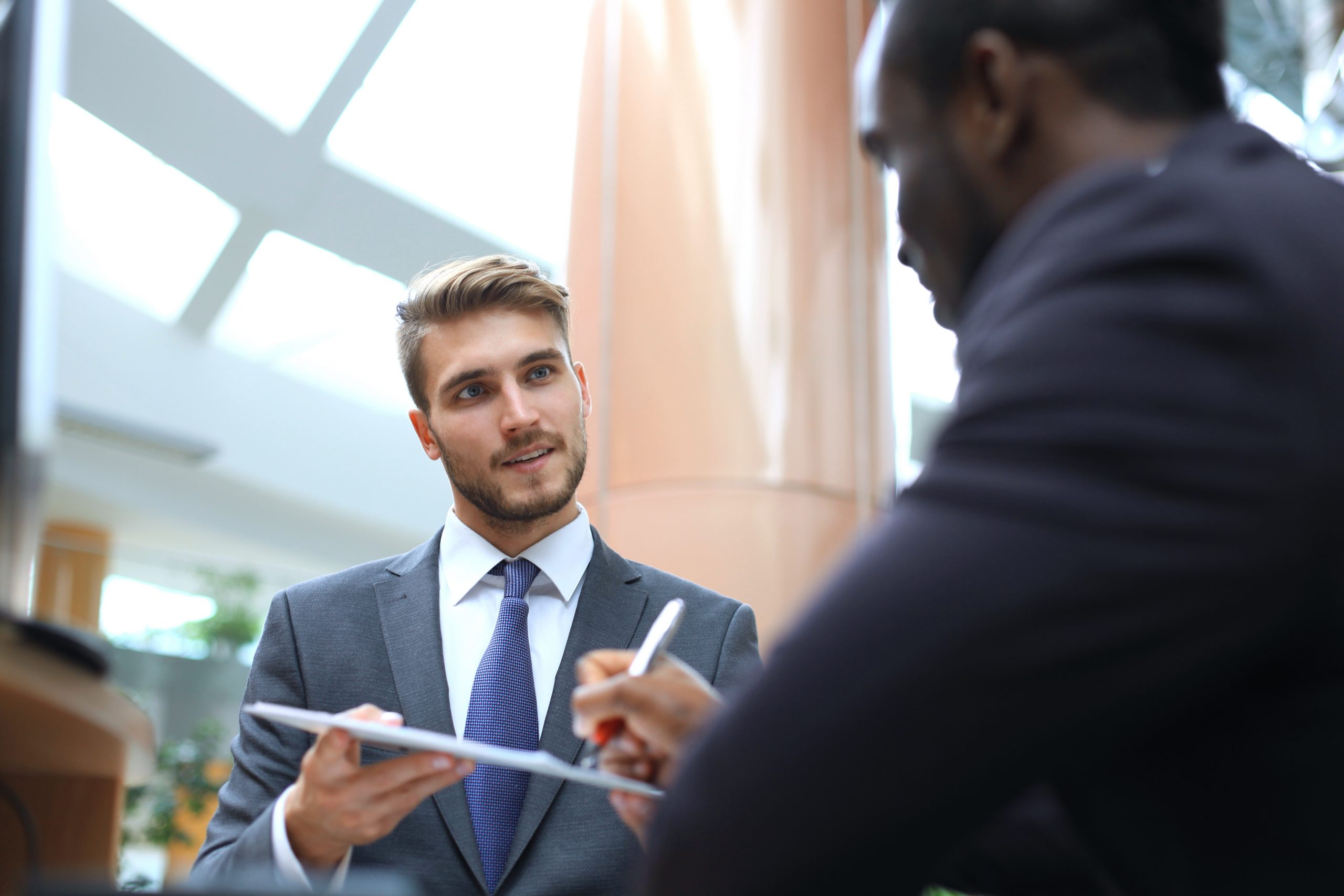 Two multinational young businessmen in suit in the office sign the contract.