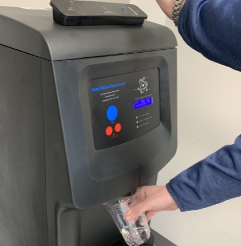 Someone filling a glass at the office water cooler to represent touchless water filling station