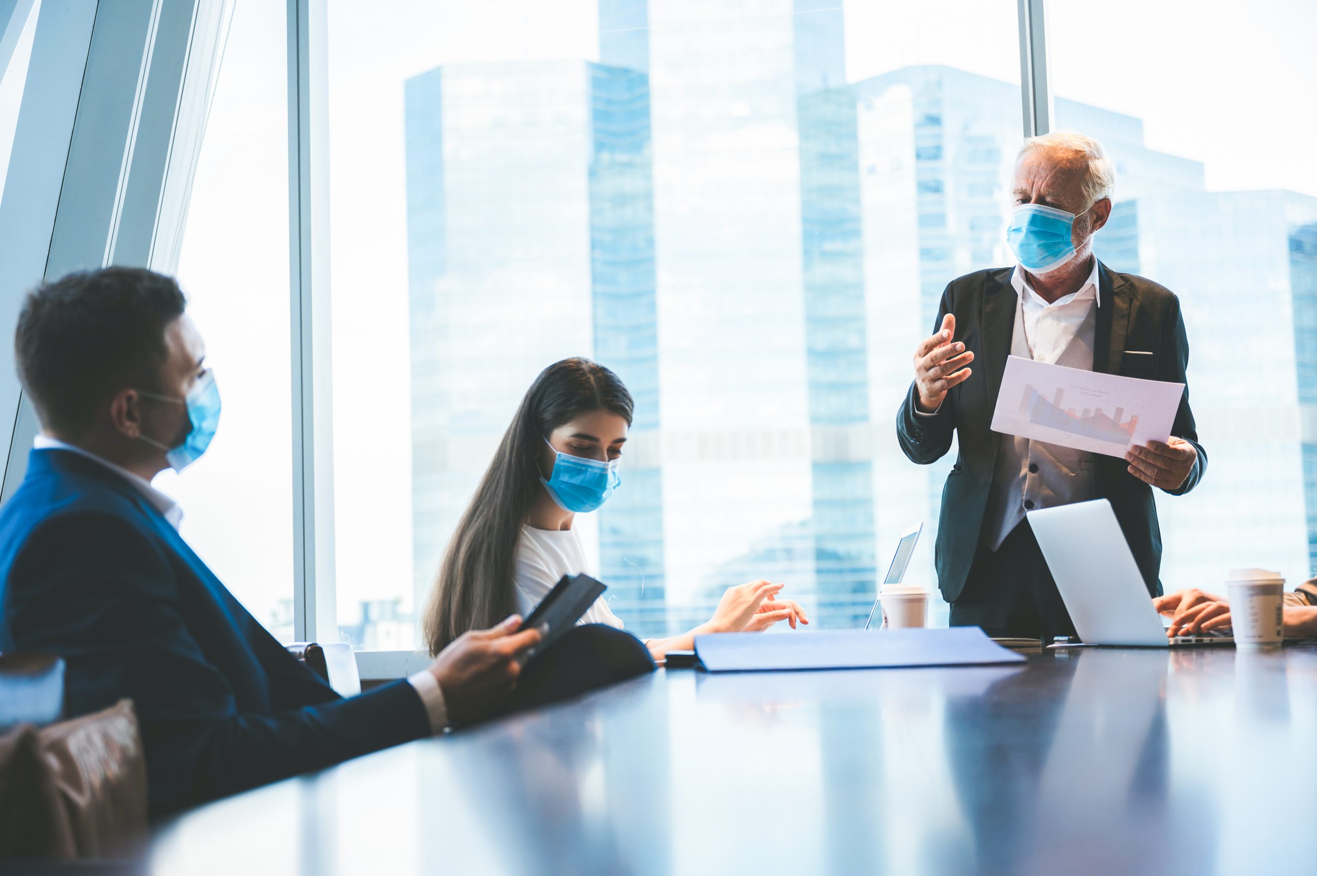 A group of businessmen meeting a work plan in modern office By wearing a surgical mask to prevent the spread of the virus, new normal lifestyle for business work