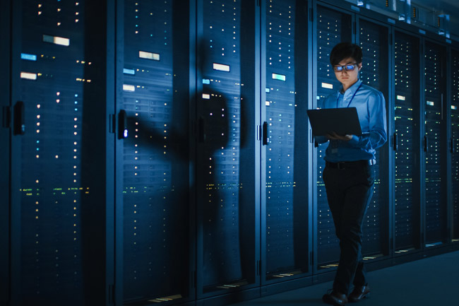 a woman in a server room to represent the importance of server availability for managed cybersecurity services