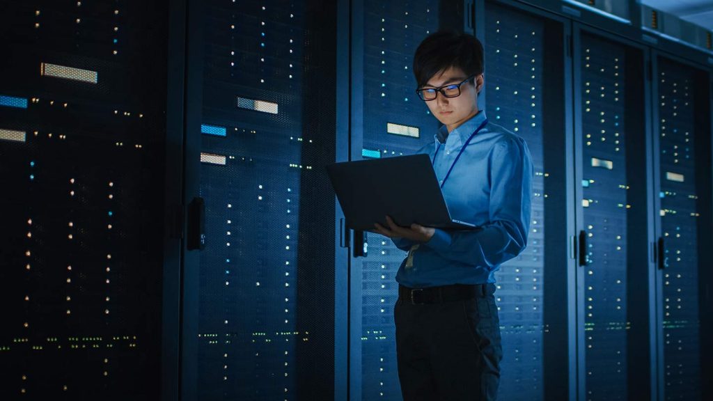 A young man checks servers to ensure data is protected and the system optimized for disaster prevention as well as recovery