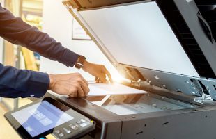 a man using an office copier to represent school office equipment