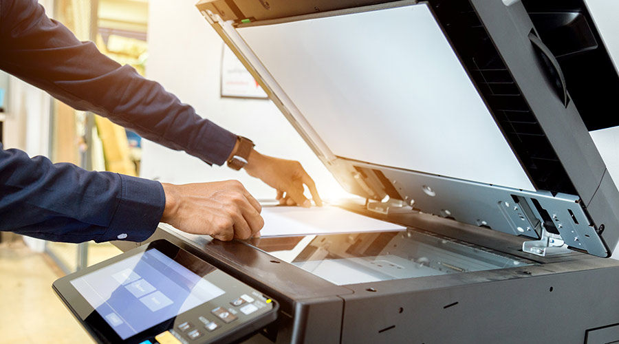 a man using an office copier to represent school office equipment