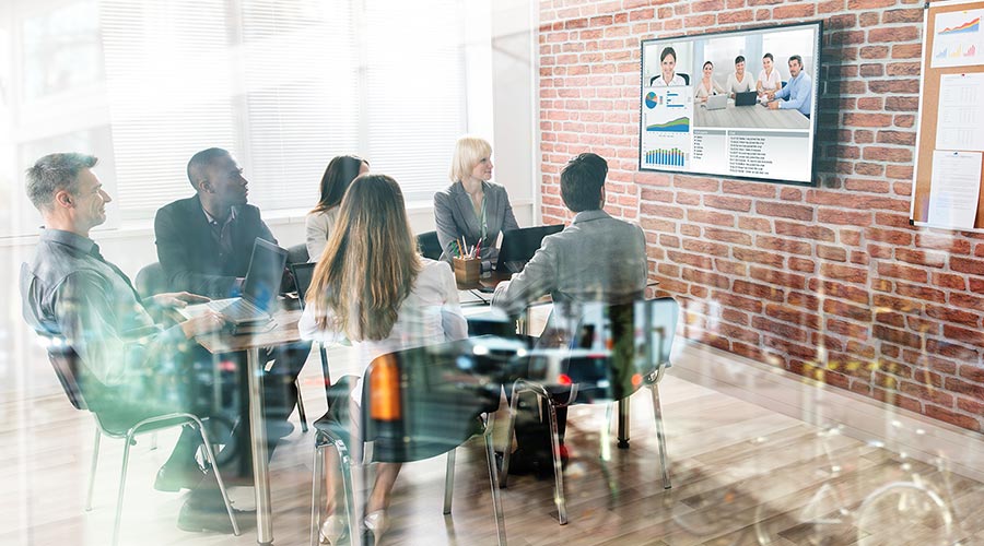 a team at the office and remote team members communicating via a video conferencing software