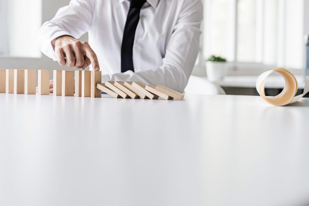 a man stopping the dominos from collapsing to illustrate what is business continuity