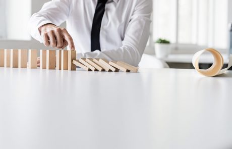 a man stopping the dominos from collapsing to illustrate what is business continuity