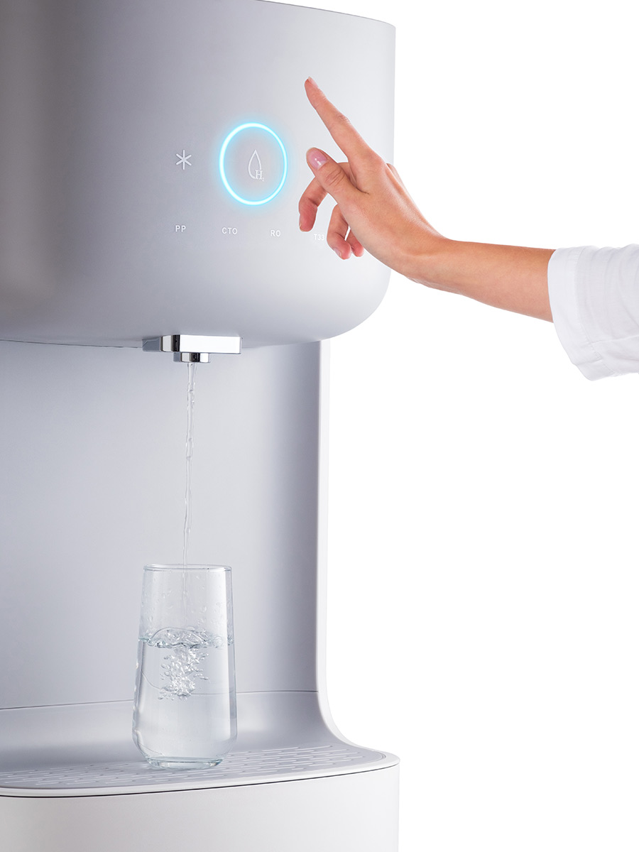 A woman using a touchless water cooler with a sensor
