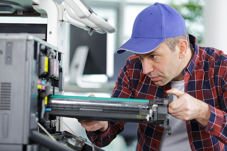 Man changing the ink cartridge of a leased copier