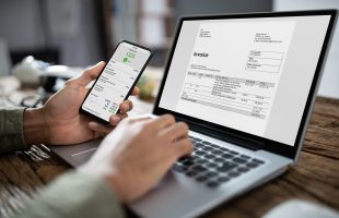 Businessman’s Hands Working On Invoice On Laptop