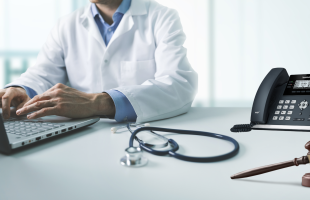 Doctor working on computer with voip system and gavel