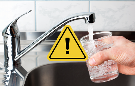 Glass of tap water with caution sign overlay